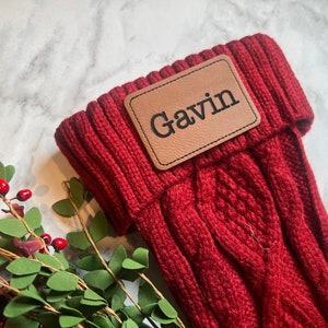 May include: Red knitted stocking with a brown leather name tag that says "Gavin".