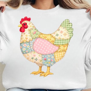 Könnte beinhalten: Weißes Sweatshirt mit einem farbenfrohen Patchwork-Hühnerdesign. Das Huhn hat einen roten Kamm und Kehllappen, gelbe Füße und einen Körper aus verschiedenen gemusterten Stoffflicken in Rosa, Grün, Gelb und Blau. Das Sweatshirt wird von einer Person getragen.