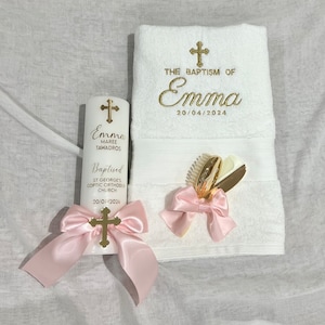 Pode incluir: Uma toalha branca com bordado dourado que diz "The Baptism of Emma 20/04/2024". Ao lado da toalha, h&aacute; uma vela branca com letras douradas e um la&ccedil;o de cetim rosa. A vela diz "Emma Maree Tawadros Batizada St George's Coptic Orthodox Church 20/04/2024".