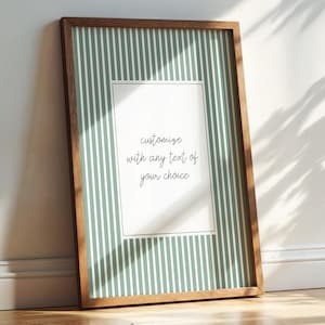 May include: A rectangular wall art print in a dark wood frame featuring a sage green background with vertical white stripes and a central white rectangular panel containing the black text, customize with any text of your choice.