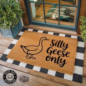 May include: A rectangular doormat with a brown coir center and a black and white checkered border. The mat features a black outline of a goose and the words "Silly Geese only" in a whimsical font.