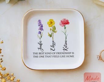 May include: White ceramic tray with a gold rim, featuring three watercolor flowers with the names Jennifer, Elissa, and Katrina written underneath. The tray has the quote "The best kind of friendship is the one that feels like home" printed on it.
