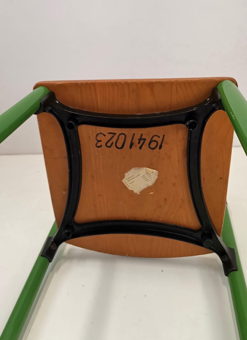 May include: The underside of a green wooden chair with black metal legs. The chair has a label with the number 1641023.