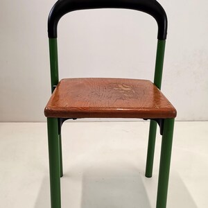 May include: A green metal chair with a black padded back and a wooden seat.