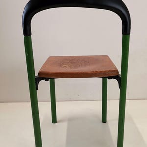 May include: A green metal chair with a black padded back and a wooden seat.