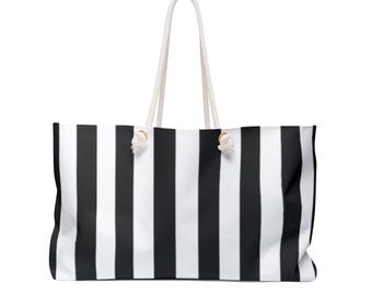 May include: A black and white striped tote bag with white rope handles. The bag features bold, vertical stripes and is designed for carrying items. The bag's design is simple and striking, with a focus on the contrasting black and white pattern. The handles are made of a thick, white rope.