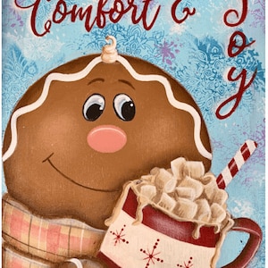 May include: A gingerbread man with a red and white scarf holds a red mug filled with marshmallows and a red and white striped straw. The background is blue with a white snowflake pattern and the text "Comfort & Joy" in red.
