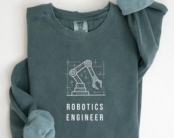 May include: A teal-colored sweatshirt with the words "ROBOTICS ENGINEER" printed in white below a white line drawing of a robotic arm. The sleeves are rolled up, showing a lighter teal interior.