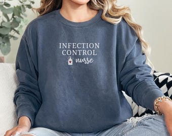 May include: A dark blue sweatshirt with the words "INFECTION CONTROL nurse" printed in white. A small graphic of a hand sanitizer bottle with a heart is below the words. The sweatshirt is a crew neck style.