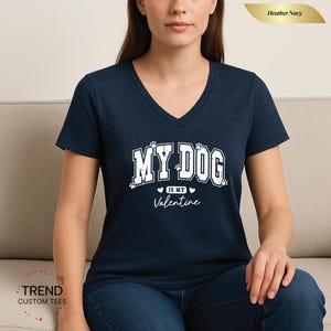 May include: Heather navy V-neck t-shirt with the text "MY DOG is my Valentine" in white. The shirt features paw prints and hearts. The shirt is made of a soft material.