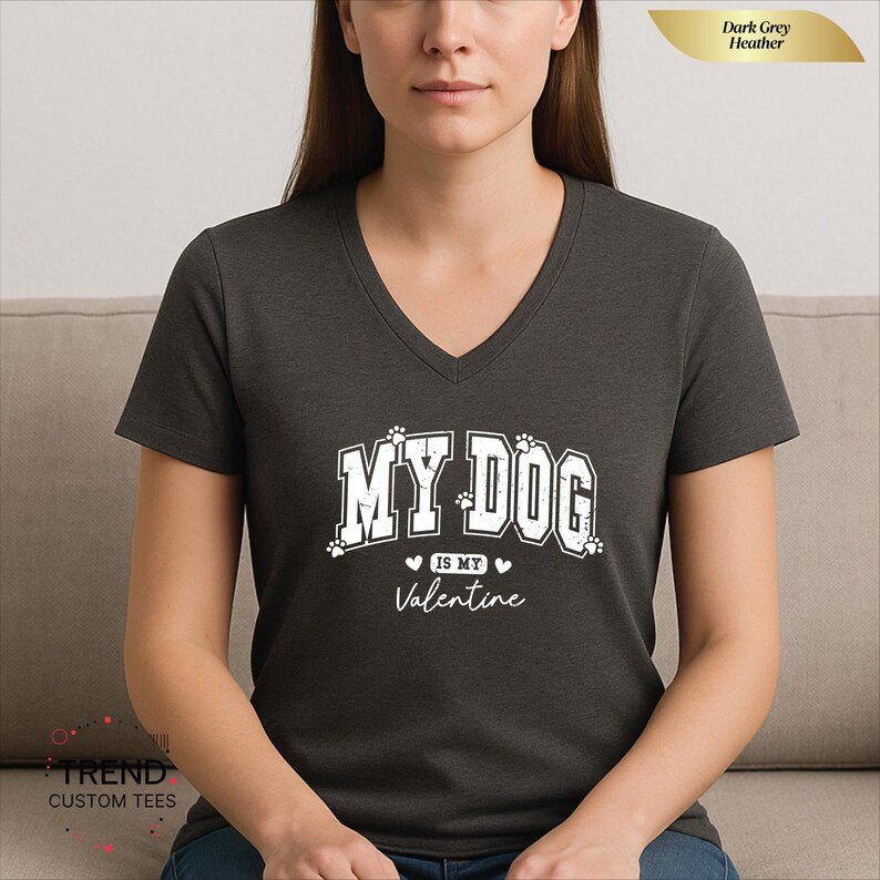 May include: Dark grey heather v-neck t-shirt with the text "MY DOG is my Valentine" in white. The text includes paw prints and hearts. The shirt is a casual style.