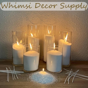 May include: Six white pillar candles in clear glass jars, with a small pile of white candle wax flakes and several white wicks on a wooden surface. The text "Whims Decor Supply" is at the top of the image.