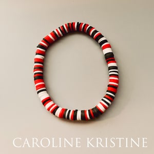 May include: A red, white, and black beaded bracelet. The beads are round and flat.
