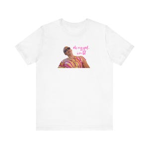 Puede incluir: Camiseta blanca con un gráfico rosa de una persona con gafas de sol y una camisa a rayas. El texto "oh my god - i'm lit" está escrito en rosa.