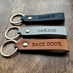 May include: Three leather keyrings with gold key rings. The keyrings are labelled "HOME", "GARAGE", and "BACK DOOR".