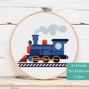 Könnte beinhalten: Kreuzstich-Stickerei eines blauen, roten und gelben Zuges mit weißem Rauch, in einem Holzreifen. Das Design ist 12,7 x 10,16 cm groß und verwendet 7 Farben. Der Zug befindet sich auf einer schwarzen Strecke.