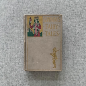 May include: A vintage book titled "Grimm's Fairy Tales" with a gold-colored title and illustrations on the cover.