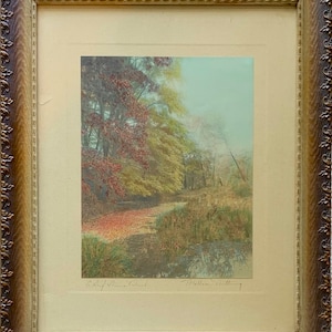 Puede incluir: Una fotografía vintage enmarcada de una escena de bosque con un arroyo en primer plano. Los árboles están en colores otoñales, con hojas rojas, amarillas y verdes. La fotografía está firmada "Ralph Clifton Packard" y "Holland Day" en la esquina inferior derecha.