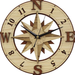 May include: A wooden wall clock with a compass design. The clock face features Roman numerals and a compass rose with the directions North, South, East, and West.