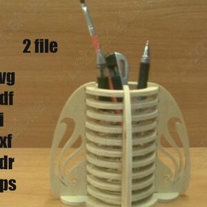 May include: A light beige wooden desk organizer with a cylindrical design, holding pens and a paintbrush. The organizer has decorative side panels and the text "2 file" and file type abbreviations: svg, pdf, ai, dxf, cdr, and eps.