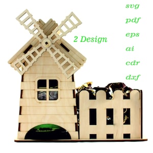 Puede incluir: Un modelo de molino de viento de madera con una pequeña casa y una valla. El molino tiene un ventilador giratorio y una pequeña ventana. El texto "2 Design" está en verde. El modelo es de madera clara.