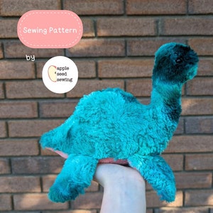 May include: A teal blue and green plush dinosaur toy with a long neck. The toy is being held in a hand. The text "Sewing Pattern by apple seed sewing" is visible in the image.