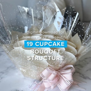 May include: A digital download for how to make a beautiful cupcake bouquet with 19 cupcakes. The cupcakes are arranged in a clear plastic wrap with white polka dots and tied with a pink ribbon.