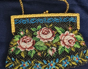 May include: A vintage beaded purse with a floral design. The purse is black with pink, green, and blue beads. It has a gold chain strap.