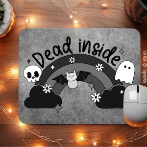 May include: A gray mousepad with the text "Dead inside" in black lettering. A rainbow with a bat, a ghost, and a skull are on the mousepad.