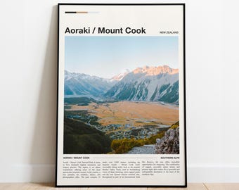 May include: A framed print featuring a scenic view of Aoraki / Mount Cook in New Zealand. The landscape includes snow-capped mountains, a valley, and a small town. The print has the text "Aoraki / Mount Cook" and "New Zealand".