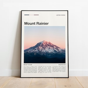Puede incluir: Una impresión enmarcada con el Monte Rainier, con el texto "Mount Rainier" y "United States". La imagen muestra la montaña bajo un cielo rosa y azul. La impresión está en un marco negro.