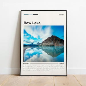 May include: A framed poster depicting Bow Lake in Banff National Park, Canada. The image shows a mountain reflected in the lake's turquoise water under a blue sky with clouds. Text on the poster reads "Bow Lake" and "Canada."