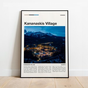 Pode incluir: Um pôster emoldurado com uma vista aérea noturna de Kananaskis Village em Alberta, Canadá. A imagem mostra edifícios iluminados aninhados em um vale com montanhas ao fundo. O pôster inclui o texto "Kananaskis Village" e "Canada".