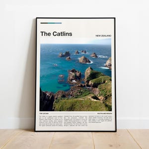 May include: A framed poster featuring a scenic view of The Catlins in New Zealand. The image showcases a turquoise ocean with rocky islands and green cliffs. The poster includes the text "The Catlins" and "New Zealand".