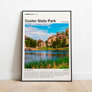 May include: A framed poster featuring a scenic view of Custer State Park in South Dakota. The image showcases a lake surrounded by green grass, trees, and rocky hills under a blue sky with clouds. The text "Custer State Park" is at the top.