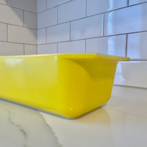 May include: A bright yellow ceramic loaf pan, perfect for baking bread or other treats.