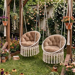 May include: Two brown cushioned hanging chairs with macramé detailing hang from a wooden pergola. The chairs are surrounded by lush greenery, flowers, and hanging planters. A serene outdoor seating area.
