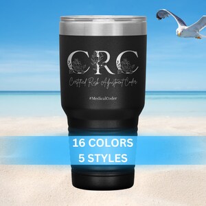 May include: A black stainless steel tumbler with a white design that says "CRC Certified Risk Adjustment Coder #MedicalCoder". The tumbler is sitting on a sandy beach with a blue sky and ocean in the background.