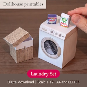 Puede incluir: Un juego de lavandería en miniatura para casa de muñecas, que incluye una lavadora, una cesta de la ropa y cajas de detergente. La lavadora es blanca con una puerta redonda. La cesta de la ropa es marrón con el interior blanco. Las cajas de detergente están etiquetadas como "ARIEL".