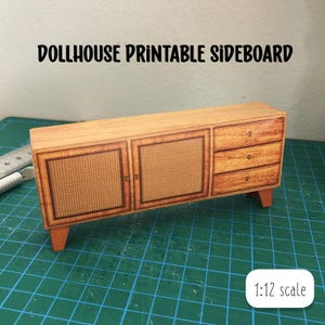 Puede incluir: Un aparador de madera marrón para casa de muñecas con dos puertas y tres cajones. Las puertas tienen un patrón de caña tejida. El aparador es a escala 1:12.