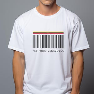 May include: White t-shirt featuring a barcode design with the colors of the Venezuelan flag at the top. Below the barcode are the words "+58 FROM VENEZUELA" in black text. The shirt is short-sleeved.