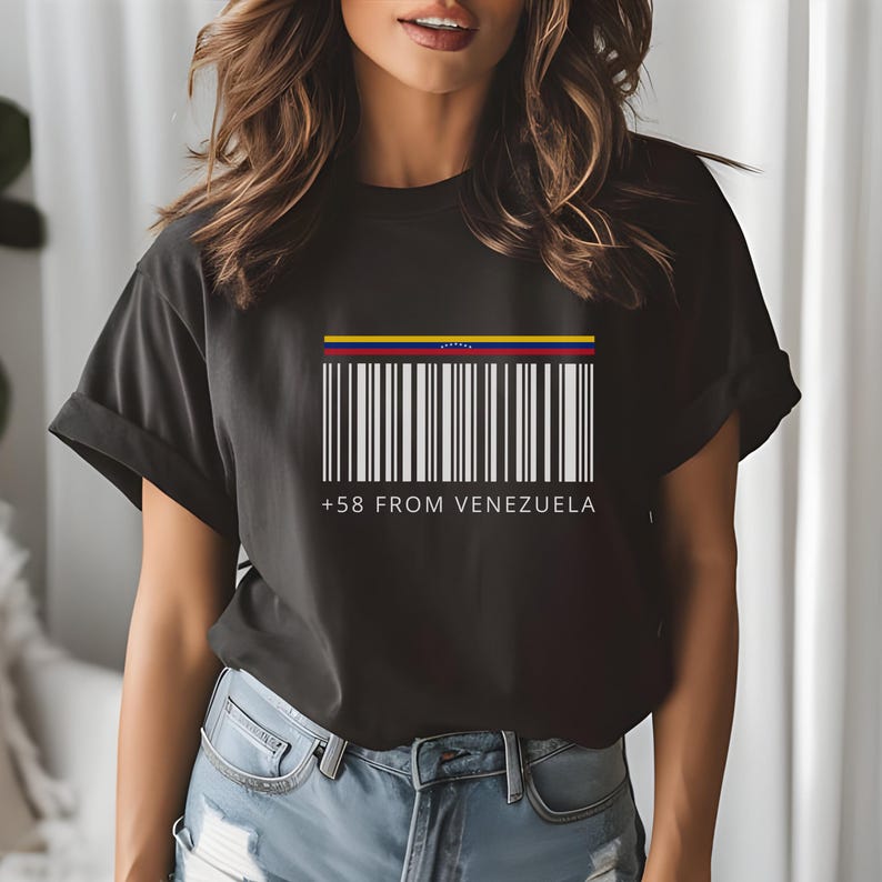 May include: Black t-shirt featuring a barcode design with the colors of the Venezuelan flag at the top. The text "+58 FROM VENEZUELA" is printed below the barcode. The shirt is a casual wear item.