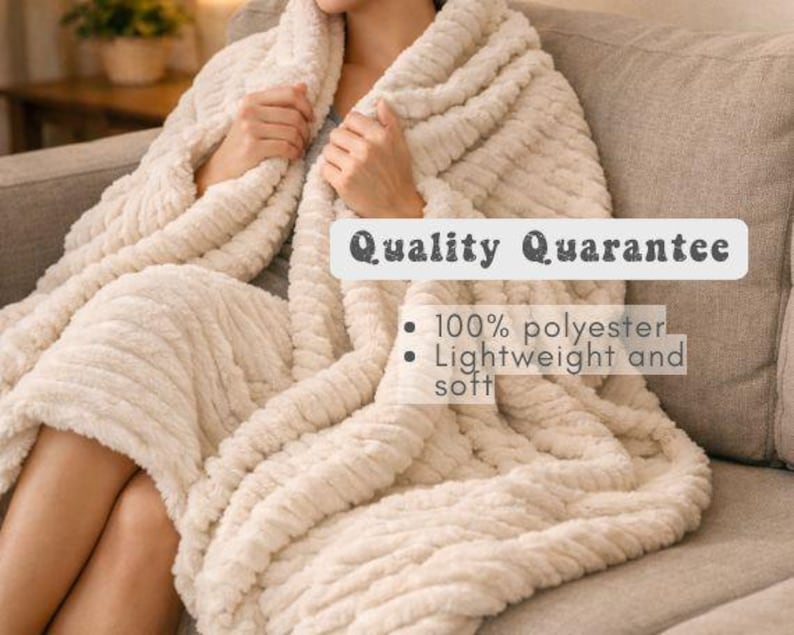 May include: A cream-colored, textured blanket draped over a person seated on a sofa. The blanket has a ribbed pattern and the text "Quality Guarantee", "100% polyester", and "Lightweight and soft".