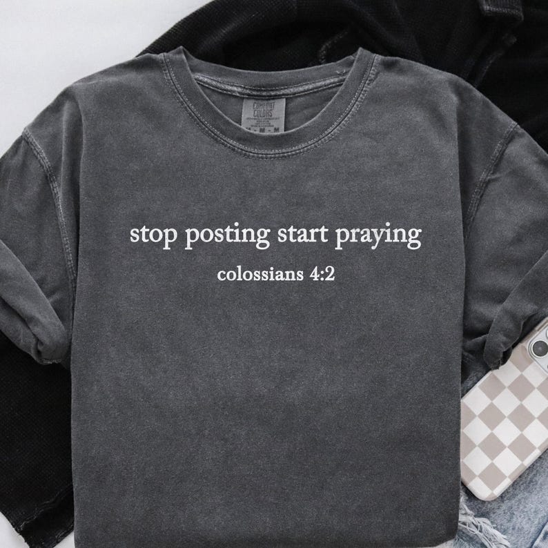 Puede incluir: Una camiseta gris oscuro con el texto "stop posting start praying" y "colossians 4:2" impreso en blanco.