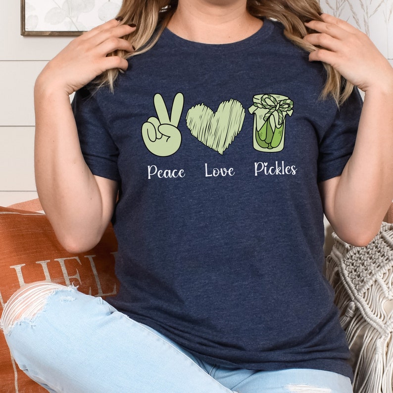 May include: A navy blue t-shirt with a peace sign, heart, and jar of pickles graphic. The text "Peace Love Pickles" is printed below the graphic.