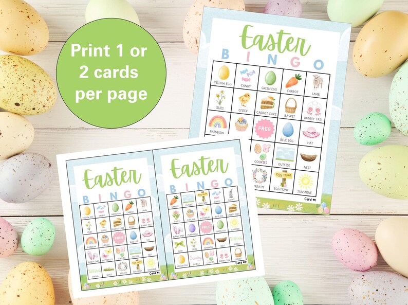May include: Two printable Easter Bingo cards with a light blue background and colorful illustrations of Easter-themed items. The cards have the text "Easter Bingo" at the top and include squares with images of a yellow egg, candy, green egg, carrot, lamb, chicks, carrot cake, basket, bunny ears, rainbow, free space, blue egg, hat, flowers, wreath, egg hunt sign, nest, sunshine, and more.