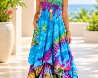 May include: A sleeveless maxi dress featuring a vibrant tie-dye pattern in shades of blue, magenta, yellow, and green. The dress has a scoop neckline, a fitted bodice, side pockets, and a layered, asymmetrical handkerchief hemline.