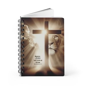 May include: A spiral bound notebook featuring a brown and white image of a lion's head gazing upwards at a wooden cross. The cross is silhouetted against a bright light. The text "Behold Jesus the Lion of Judah Revelation 5:5" is printed on the cover.