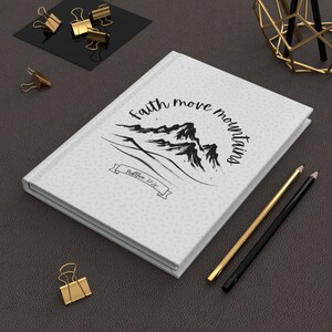 May include: White journal with a black and white illustration of mountains and the text "Faith move mountains" and "Matthew 17:20".