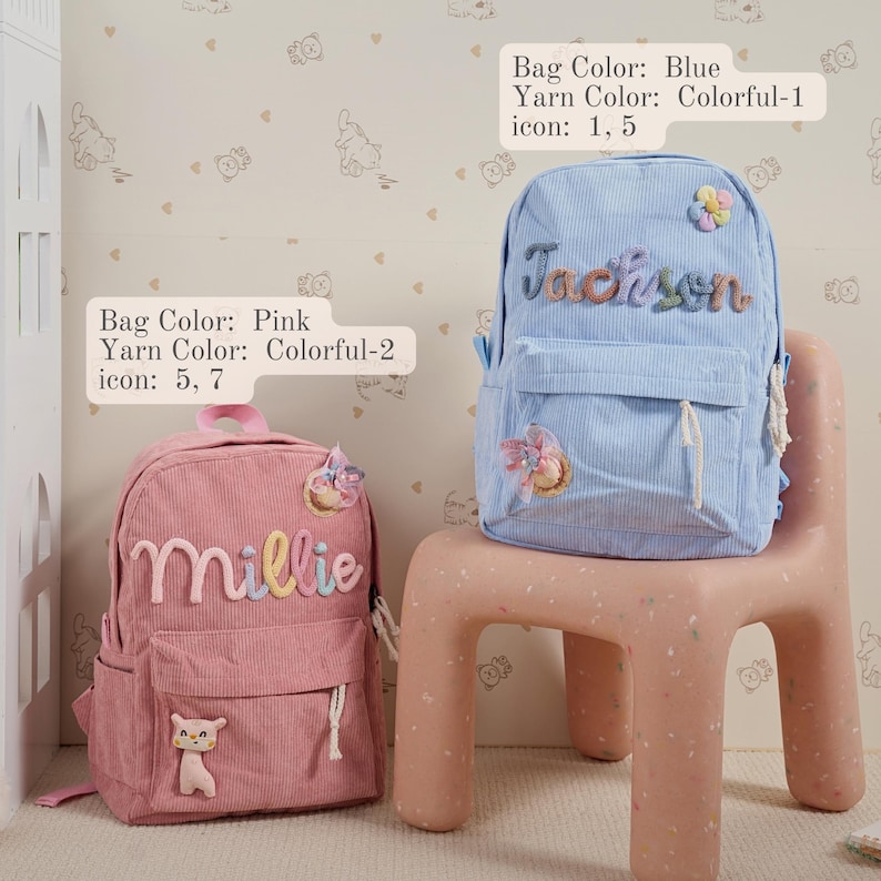 Op de afbeelding: Twee corduroy rugzakken, &eacute;&eacute;n roze en &eacute;&eacute;n blauw, staan op een roze stoel. De roze rugzak heeft de naam "Millie" erop geborduurd, en de blauwe rugzak heeft de naam "Jackson". Beide hebben bloemversieringen.